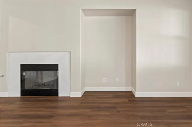 a view of an empty room with wooden floor and a fireplace
