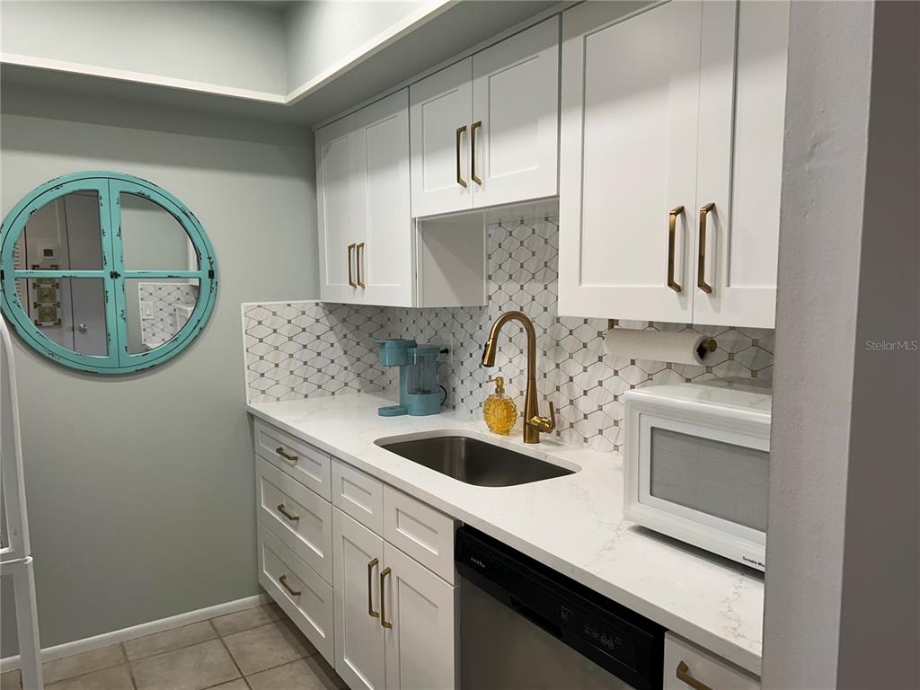 8625 Midnight Pass Road, Unit 305B Sarasota, FL 34242 - Photo 11 of 38 a kitchen with cabinets a sink and a stove top oven