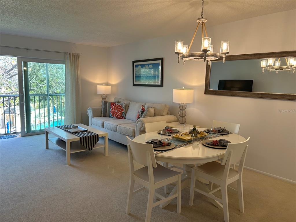 8625 Midnight Pass Road, Unit 305B Sarasota, FL 34242 - Photo 10 of 38 a living room with furniture a chandelier and a dining table