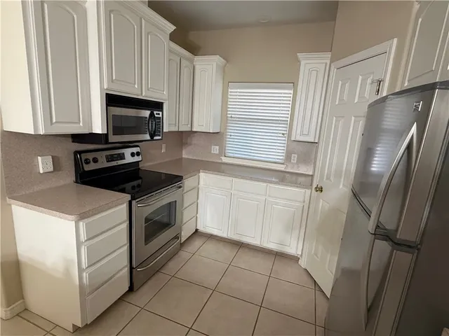 a kitchen with white cabinets and white appliances