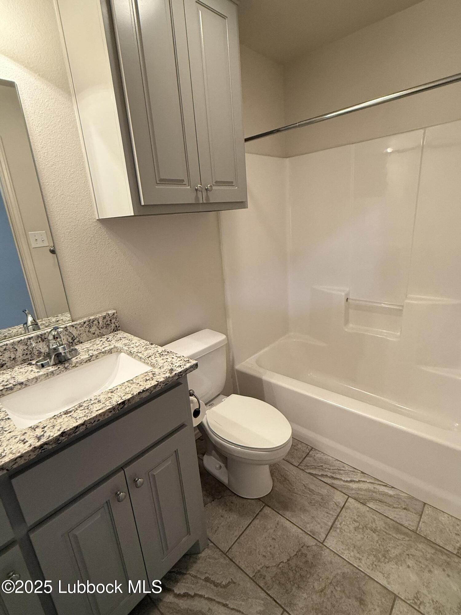 6711 Pontiac Avenue, Unit 12 Lubbock, TX 79424 - Photo 13 of 14 a bathroom with a granite countertop sink toilet and shower