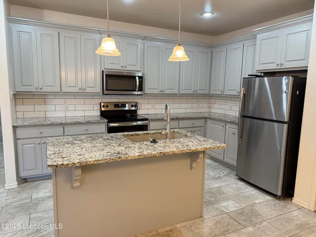 a kitchen with stainless steel appliances granite countertop a refrigerator stove a sink and a microwave