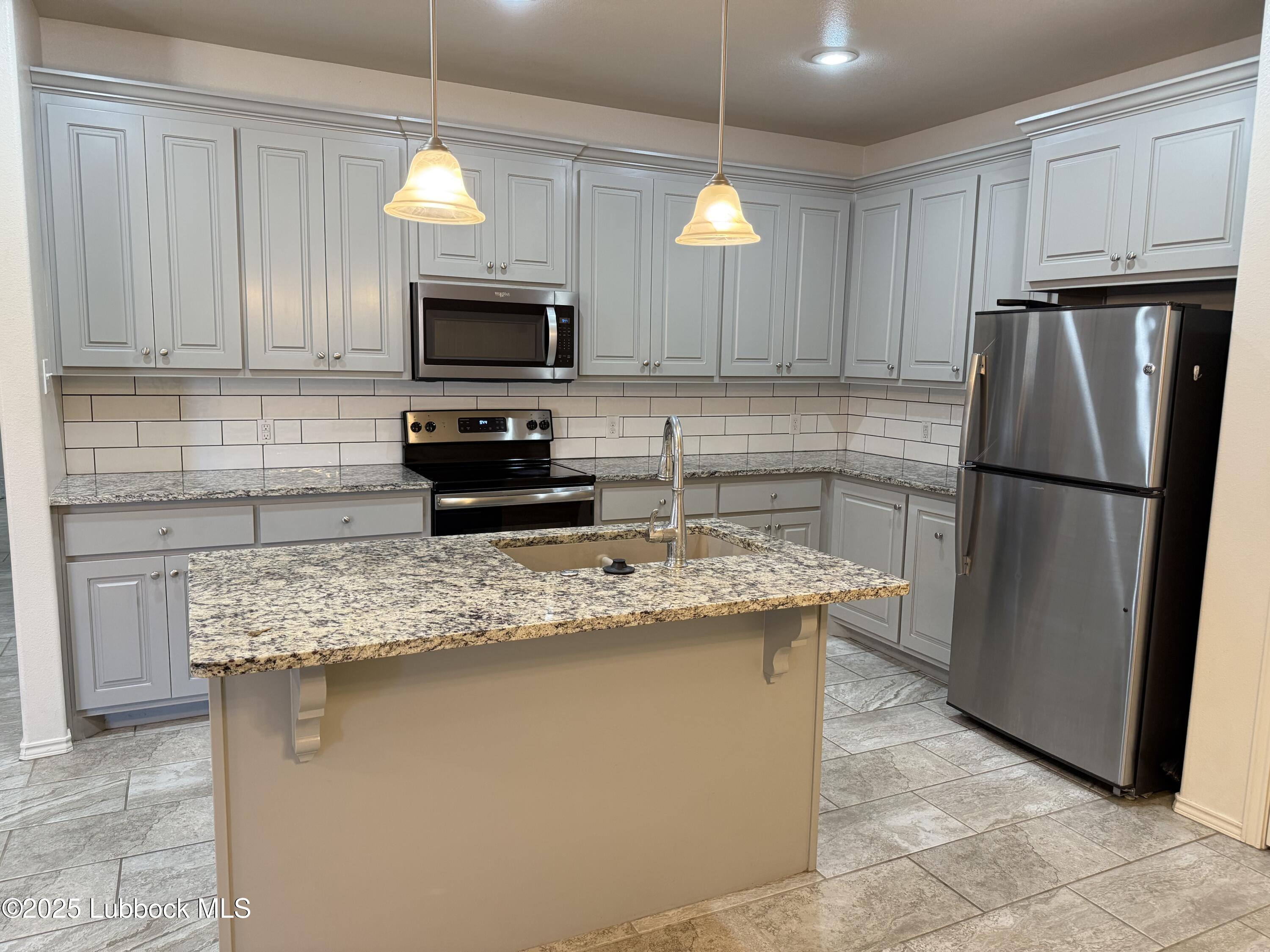 6711 Pontiac Avenue, Unit 12 Lubbock, TX 79424 - Photo 3 of 14 a kitchen with stainless steel appliances granite countertop a refrigerator stove a sink and a microwave