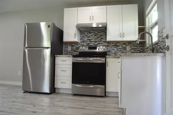a kitchen with stainless steel appliances a refrigerator stove and cabinets