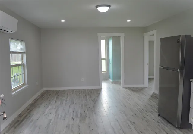 a view of an empty room with window and wooden floor