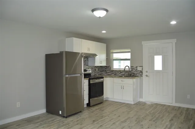 a kitchen with granite countertop a refrigerator and a stove top oven