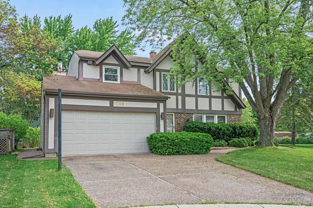 a front view of a house with a garden and trees