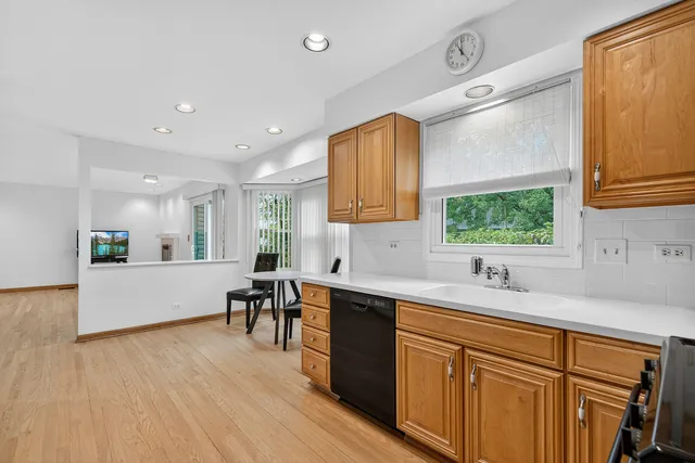 a large kitchen with stainless steel appliances a sink dishwasher a stove a microwave oven and a dining table with wooden floor