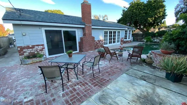 a view of a patio with table and chairs potted plants and a large tree