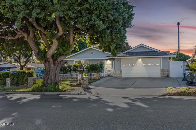 a front view of a house with a garden and trees