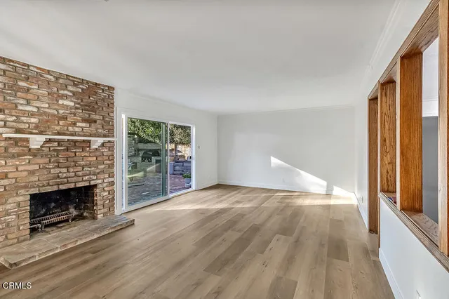a view of empty room with wooden floor and fireplace