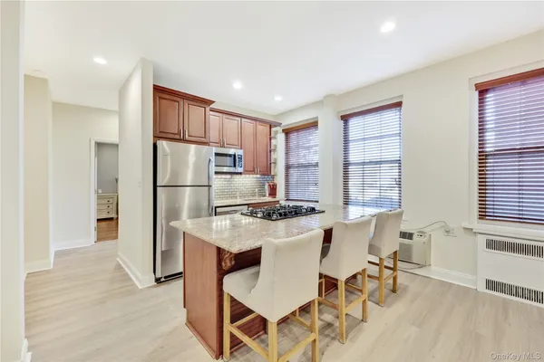 a kitchen with stainless steel appliances kitchen island granite countertop a refrigerator a stove a dining table and chairs