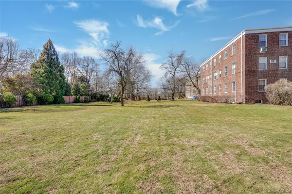 a view of a building with a big yard and a large trees