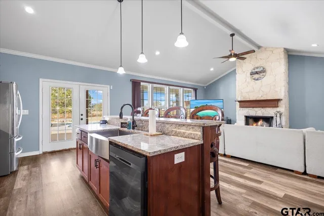 a kitchen with stainless steel appliances granite countertop a stove a sink dishwasher and a refrigerator with wooden floor