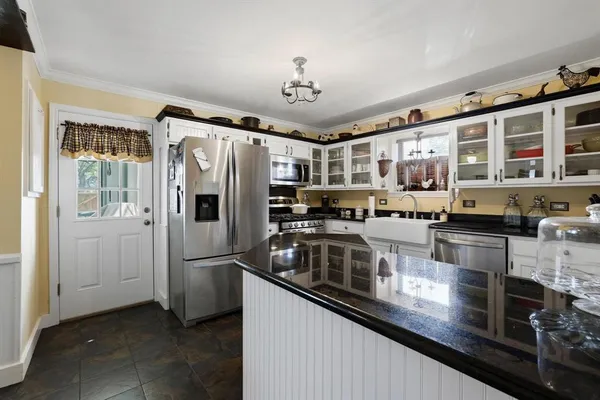 a kitchen with stainless steel appliances granite countertop a refrigerator a stove and a sink with wooden floor
