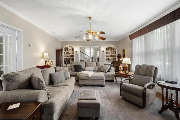 a living room with furniture a large window and a chandelier