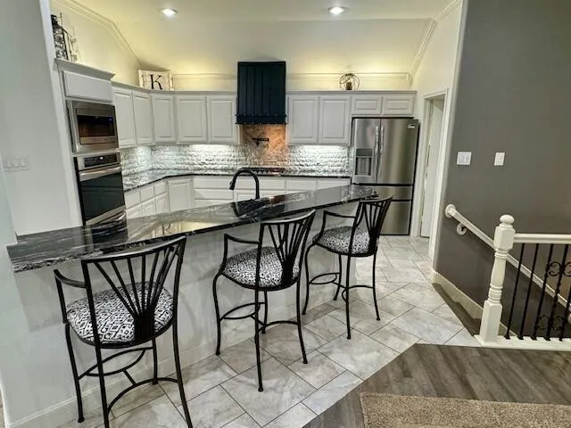 a kitchen with stainless steel appliances kitchen island granite countertop a table chairs microwave and sink