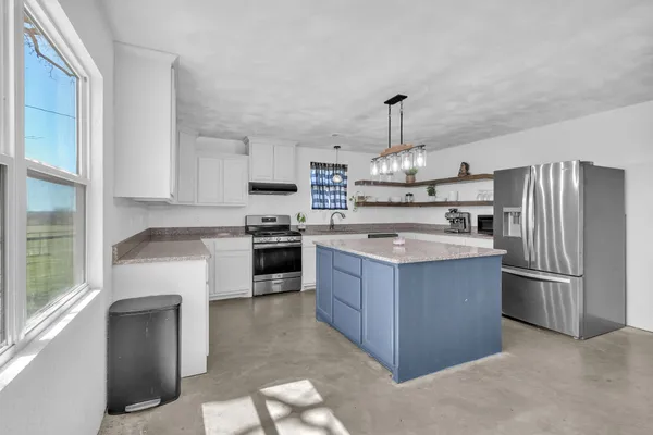 a kitchen with stainless steel appliances granite countertop a stove top oven a refrigerator and a sink with wooden floor