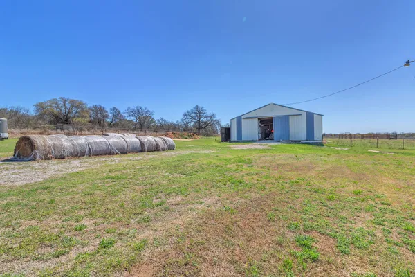 a view of a house with a yard and a large tree