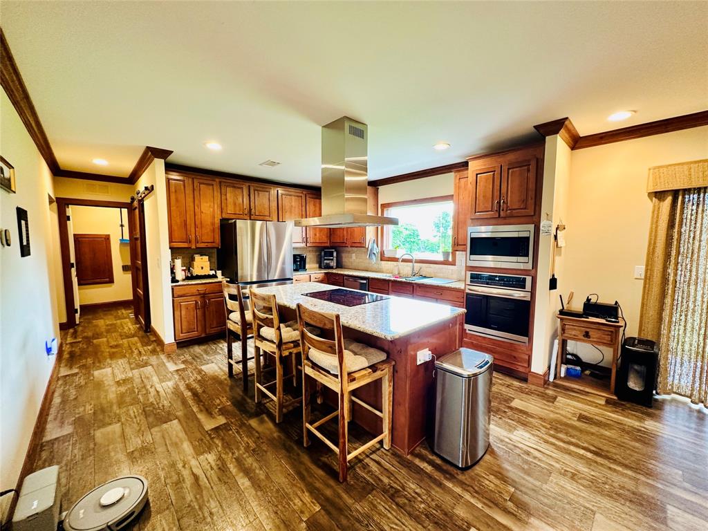 251 County Road 225 Rising Star, TX 76471 - Photo 12 of 40 a kitchen with stainless steel appliances kitchen island granite countertop a table chairs in it and wooden floors