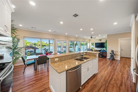 a large kitchen with kitchen island a stove a sink a refrigerator and white cabinets with wooden floor