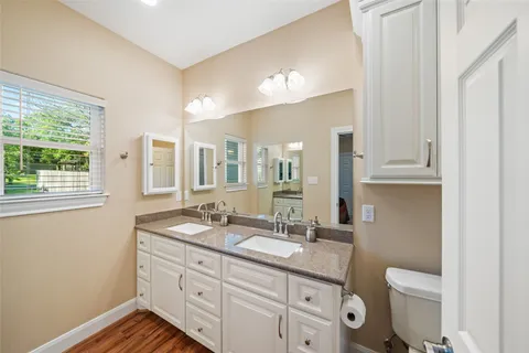 a bathroom with a granite countertop sink a toilet a mirror and shower