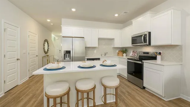 a kitchen with stainless steel appliances granite countertop a sink a stove a kitchen island and chairs