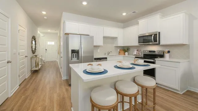a kitchen with stainless steel appliances granite countertop a kitchen island a stove a table and chairs in it