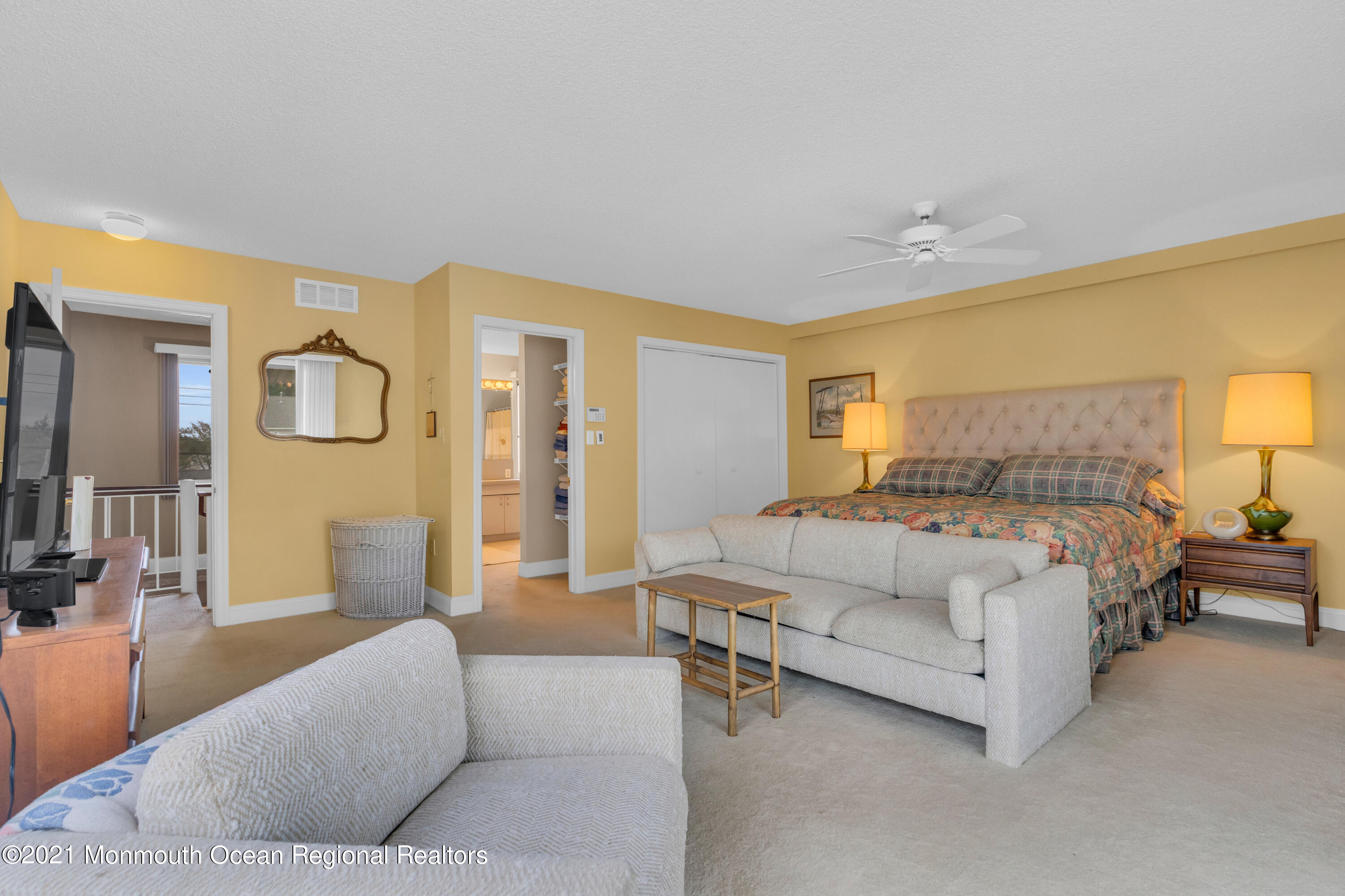 59 Cedar Run Road Bayville, NJ 08721 - Photo 24 of 32 a spacious bedroom with a bed a couch and a lamp on dresser