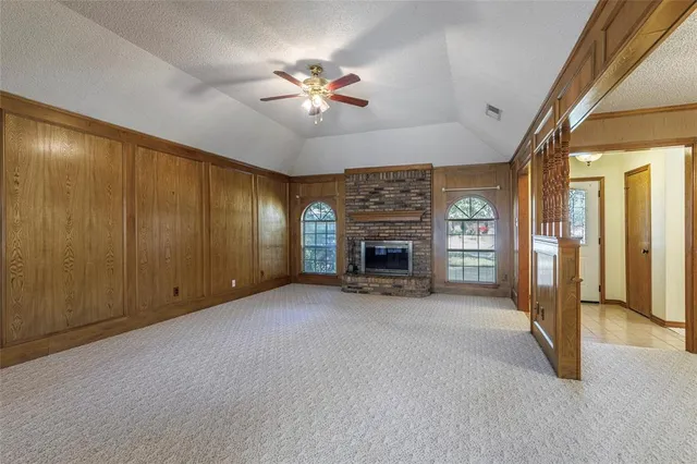 an empty room with fan fireplace and windows