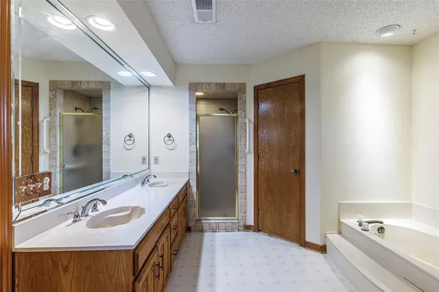 a bathroom with a tub sink double vanity and mirror