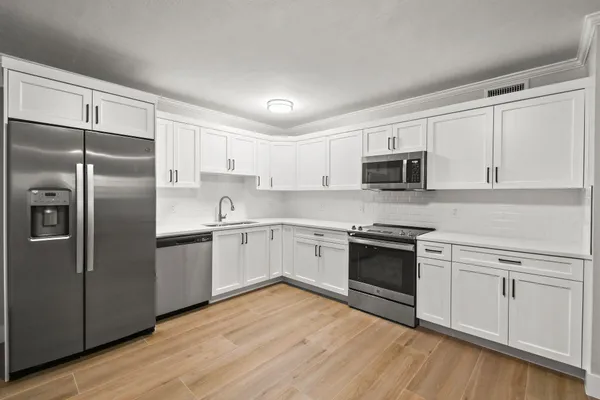 a kitchen with cabinets stainless steel appliances and wooden floor