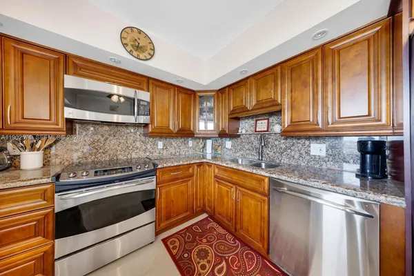 a kitchen with granite countertop cabinets stainless steel appliances and a counter space
