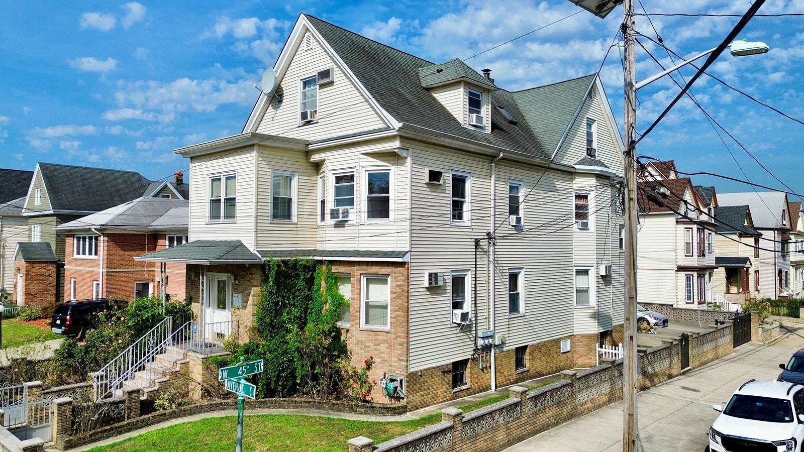 961 Avenue C Bayonne, NJ 07002 - Photo 2 of 21 a view of a white house with large windows and a yard