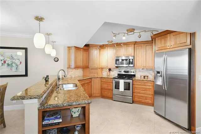 a kitchen with stainless steel appliances granite countertop a stove a refrigerator and a sink