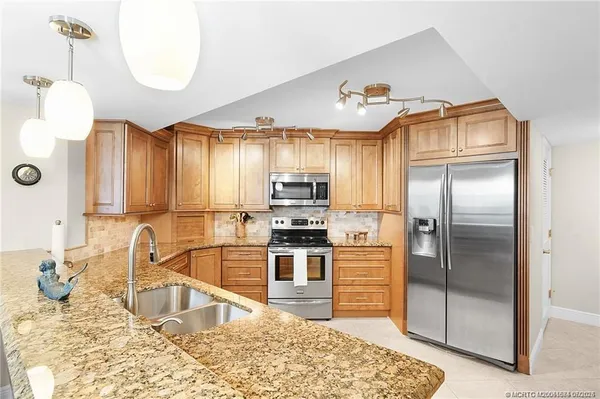 a kitchen with kitchen island granite countertop a sink refrigerator and cabinets