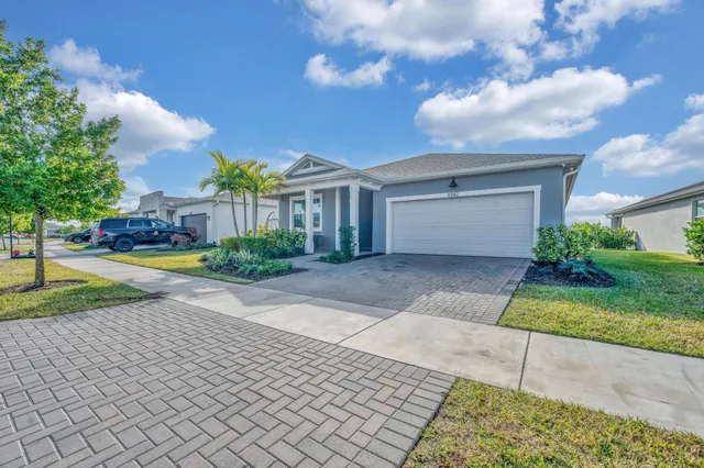 a view of a white house with a yard and a large tree