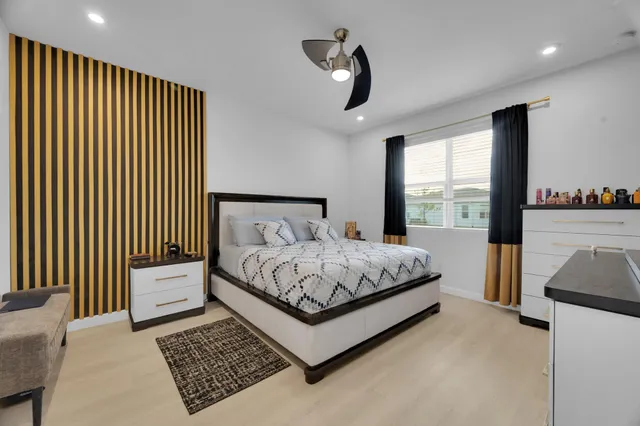 a bedroom with a bed lamp and a large window