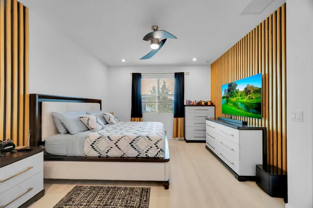 a bedroom with a large bed and a flat tv screen on dresser