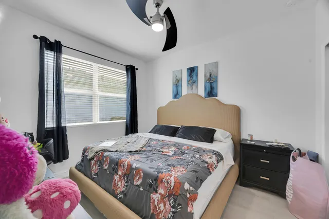 a bedroom with a bed and dresser with wooden floor