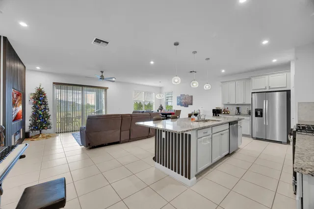 a kitchen with stainless steel appliances kitchen island granite countertop a refrigerator a sink and a stove