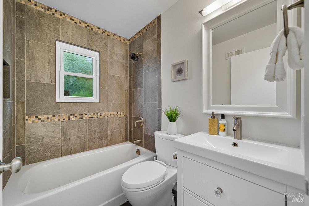934 Las Pavadas Avenue San Rafael, CA 94903 - Photo 25 of 36 a bathroom with a granite countertop toilet a sink a mirror a bathtub and shower