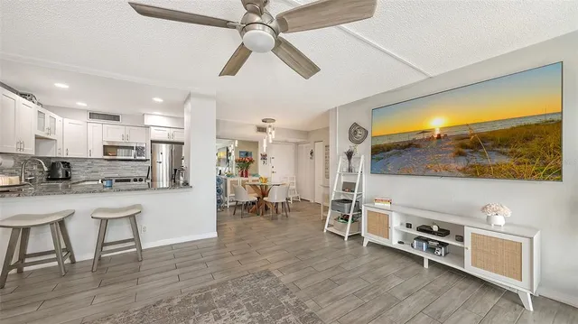 a living room with stainless steel appliances furniture and a flat screen tv