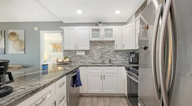 a kitchen with stainless steel appliances granite countertop a sink stove refrigerator and cabinets