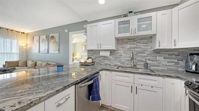a kitchen with granite countertop a sink a stove and cabinets