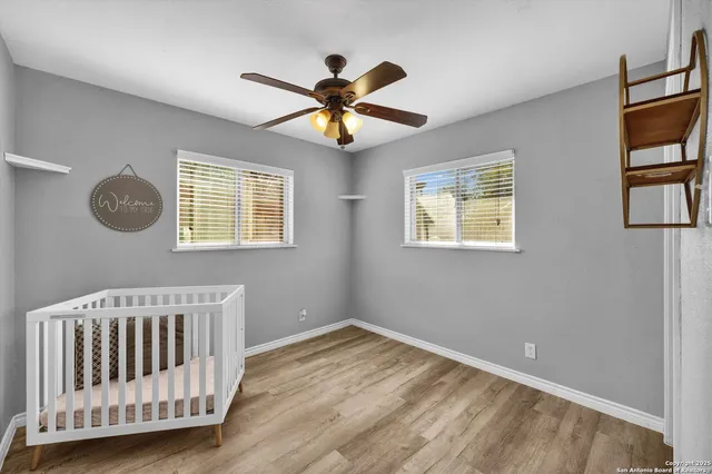 a view of a bedroom with wooden floor and windows