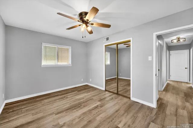 a view of empty room with wooden floor and fan