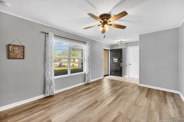 a view of an empty room with window and wooden floor