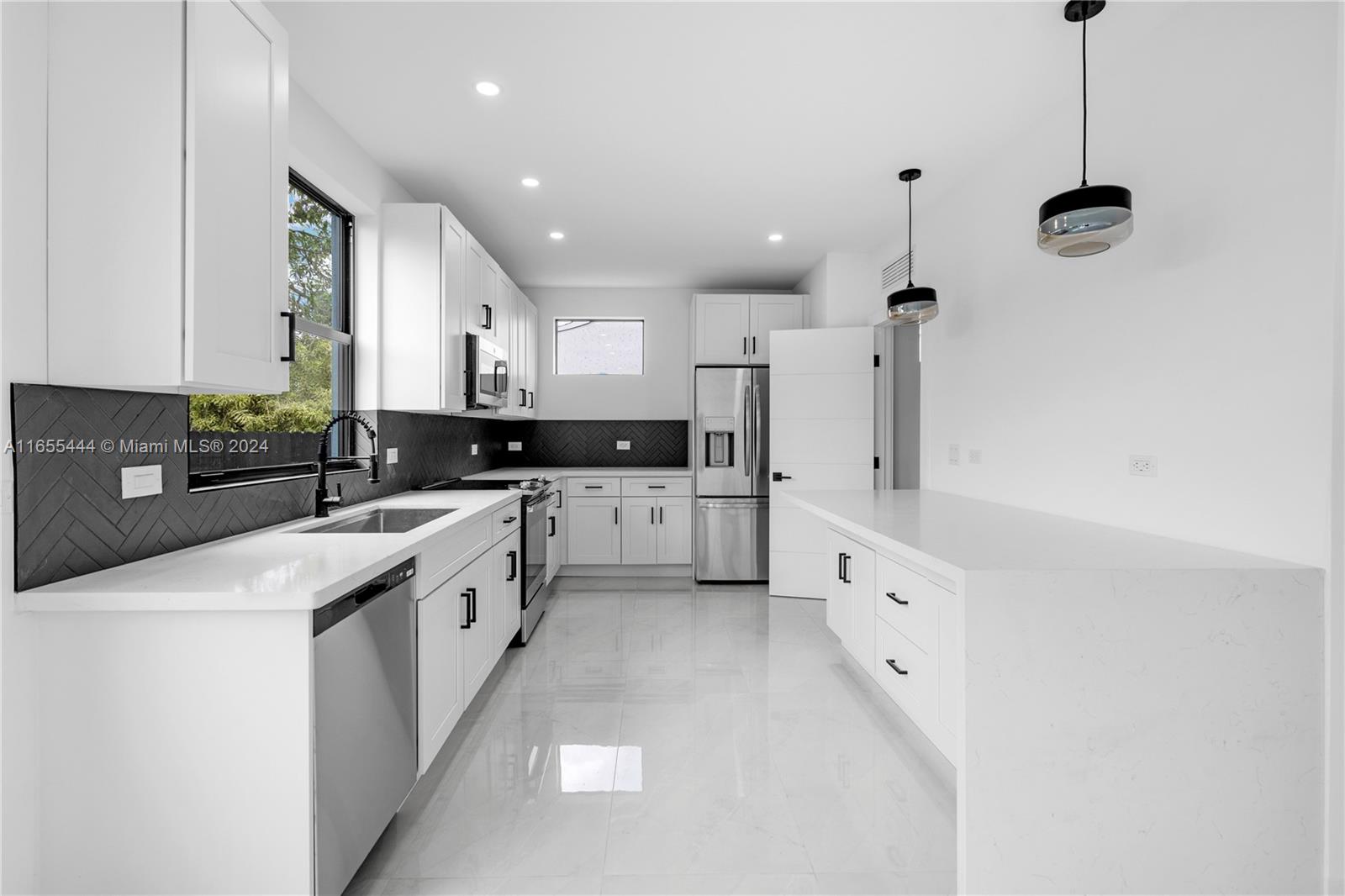 2340 Southwest 13th Street, Unit 2340 Miami, FL 33145 - Photo 4 of 26 a large kitchen with stainless steel appliances kitchen island granite countertop a sink a stove a refrigerator a window and white cabinets