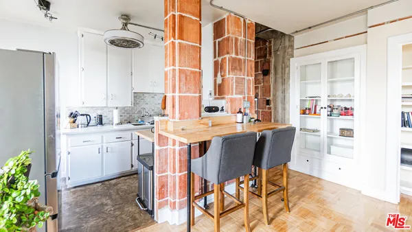 a dining room with stainless steel appliances kitchen island granite countertop a table chairs in it and a window